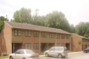 Shows the entrance and parking of a series of apartment buildings that contain parking stalls beneath them