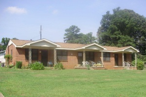 Shows the front of a three unit, brick, rowhouse