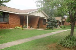 Shows an angle view of a series of single story brick row house entrances